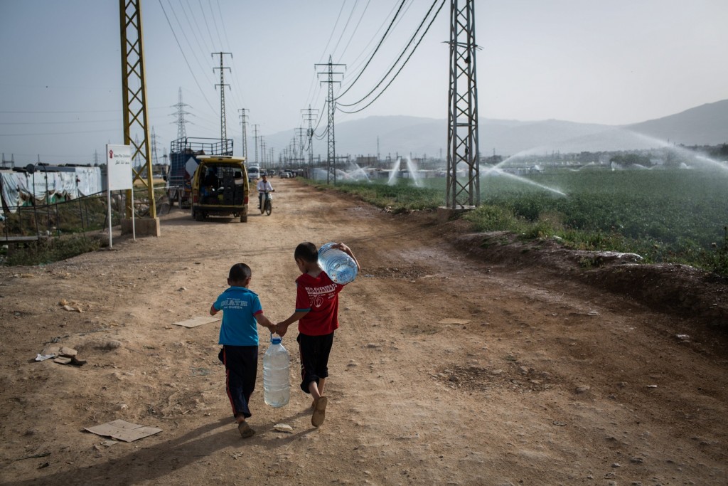 Lebanon / Syrian Refugees / Young Syrian refugees return to their shelters with water, at the Fayda informal settlement in the Bekaa Valley, Lebanon, on June 4, 2014. UNHCR / A. McConnell / June 2014
